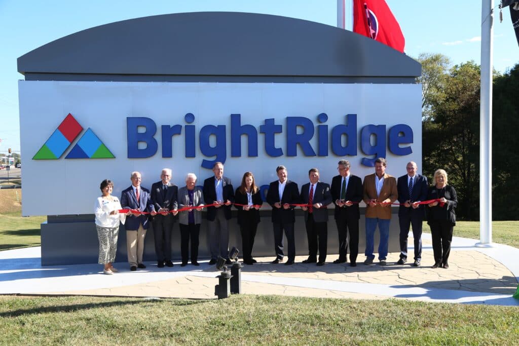 A group of people participate in a ribbon-cutting ceremony in front of the BrightRidge sign, under a clear sky, possibly celebrating an opening or event.