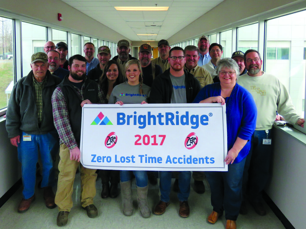 A group of people smiling and holding a "BrightRidge 2017 Zero Lost Time Accidents" sign in an office-like corridor, celebrating a safety milestone.